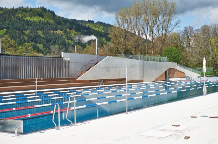 Schwimmerbecken, dahinter die Garderobengebäude mit Holzterrasse