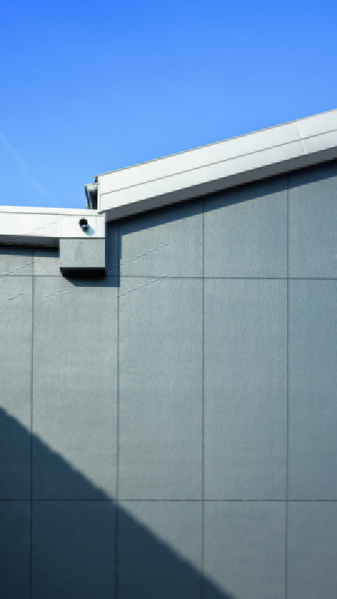 Fassadendetail eines Gewerbebaus in Fresens (CH) mit Hardie® Architectural Panel (Oberfläche Gebürsteter Beton, Anthrazitgrau)
